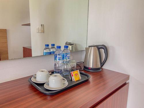 a tray with cups and water bottles on a counter at Mandhasativa Homestay in Singaraja