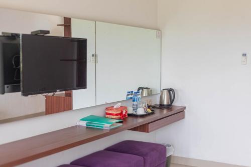 a living room with a tv and a purple stool at Mandhasativa Homestay in Singaraja