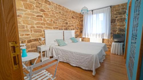 a bedroom with a bed and a stone wall at Posada Venta Hornizo in Arenas de Iguña