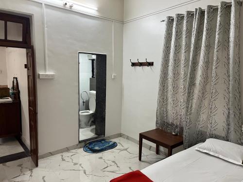 ein Schlafzimmer mit einem Bett und ein Badezimmer mit einem WC in der Unterkunft Hotel Laxminarayan Niwas in Pune