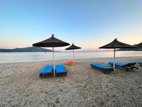 three chairs and umbrellas on a beach with the ocean at Karaburun Sunset Beach in Orikum