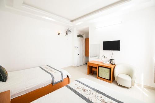 a bedroom with two beds and a desk and a television at Hồng Tâm Hotel in Da Lat