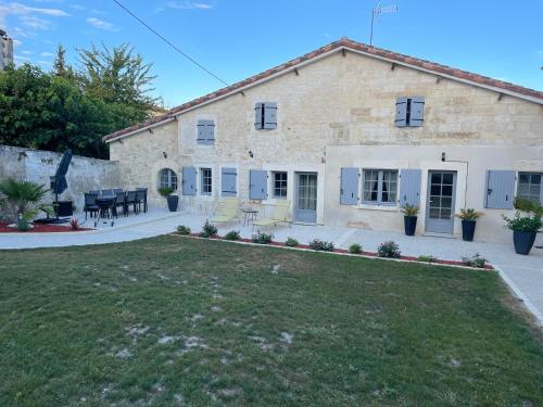a large stone house with a lawn in front of it at Gîte La Rive Gauche in Saint-Même-les-Carrières