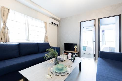 a living room with a blue couch and a table at Ra premier K Osaka NAMBA Shinsaibashi USJ Shinimamiya Hanazonocyo in Osaka