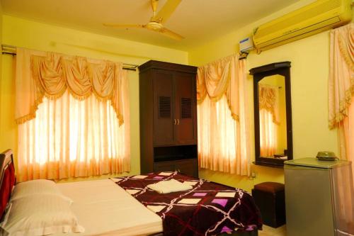 a bedroom with a bed and two windows at Vrindavan Suites Guruvayur in Guruvāyūr
