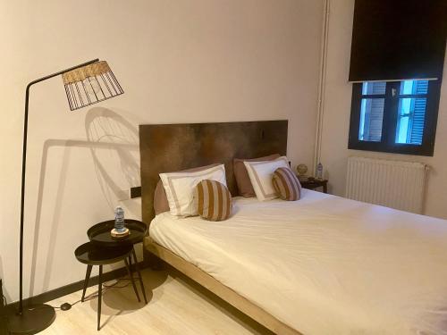 ein Schlafzimmer mit einem weißen Bett mit Kissen und einer Lampe in der Unterkunft Trésors de la Cathédrale, Maison de Ville sur 4 niveaux in Narbonne