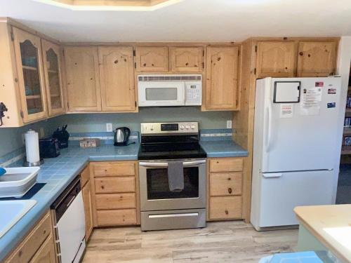 a kitchen with white appliances and wooden cabinets at Squirrel View Hot tub BBQ Patio Shuffle Board in Oakhurst