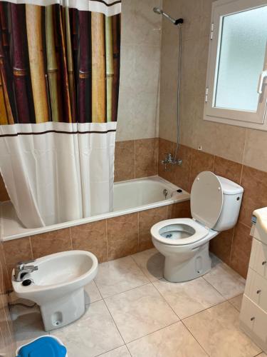y baño con aseo y cortina de ducha. en Amplio Apartamento con acceso directo a piscina, en Platja d'Aro