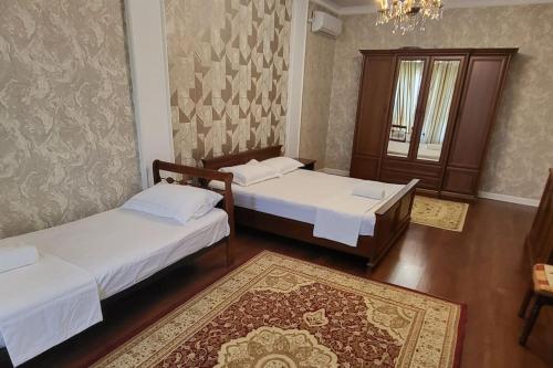 アルマトイにあるAlmaty guest houseのベッド2台とシャンデリアが備わる客室です。