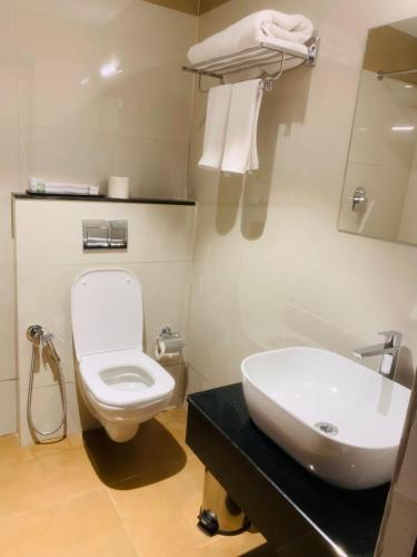 a bathroom with a white toilet and a sink at Rajathadri Royal Inn in Bangalore