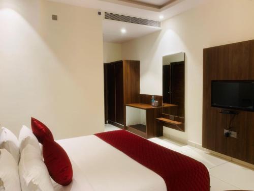 a bedroom with a bed with red pillows and a tv at Rajathadri Royal Inn in Bangalore