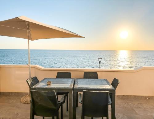 einen Tisch mit Stühlen und einen Regenschirm auf einem Boot in der Unterkunft Appartamento Fronte Spiaggia con Terrazza Vista Mare in Bonifati