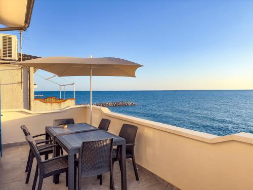 einen Tisch und Stühle auf einem Balkon mit Meerblick in der Unterkunft Appartamento Fronte Spiaggia con Terrazza Vista Mare in Bonifati
