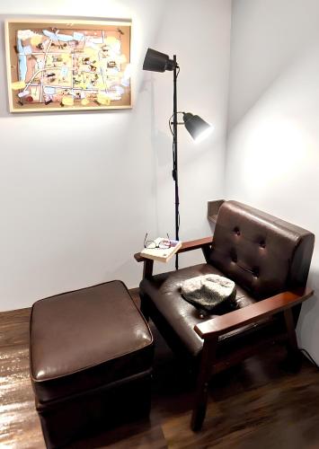 a living room with a leather chair and a lamp at Journey Town Inn in Taipei
