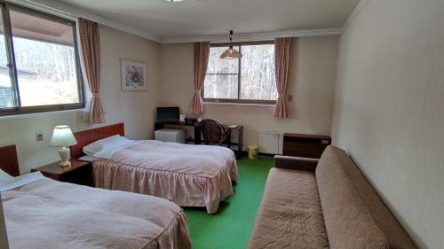小谷村にある味なお宿 松ノ木亭のベッド2台とソファが備わるホテルルームです。