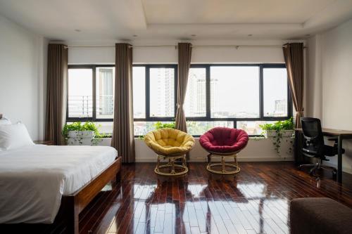 a bedroom with two chairs and a bed and windows at ALEAH HOME in Hanoi