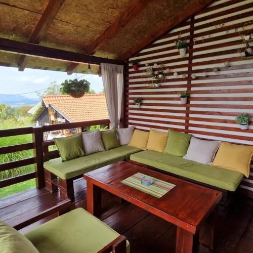 eine abgeschirmte Veranda mit grünen Sofas und einem Tisch in der Unterkunft ZOĆEVIĆA KONAK in Petrovići