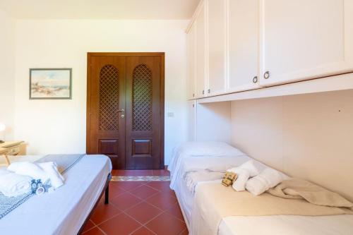 two beds in a room with a door at [PORTO CERVO] Accanto alla spiaggia & vista Mare in Porto Cervo