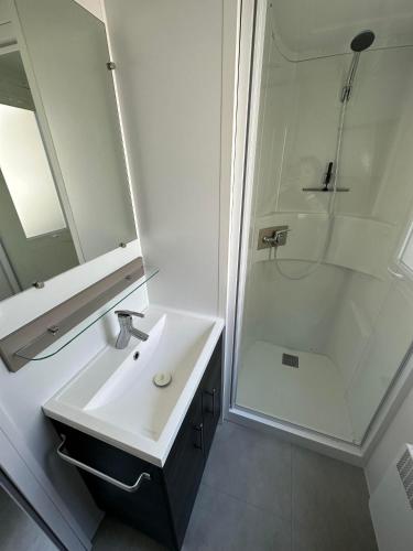 une salle de bain blanche avec un lavabo et une douche dans l'établissement Camping 4 étoiles Le bois dormant, à Saint-Jean-de-Monts