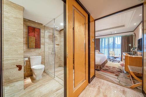 a bathroom with a toilet and a bedroom at Nanning Landmark Hotel in Nanning
