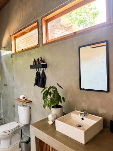 a bathroom with a sink and a toilet and a window at Casa Flores in Kuta Lombok
