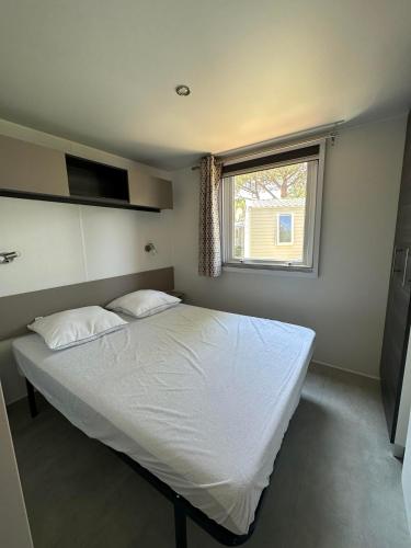 une chambre avec un grand lit blanc avec une fenêtre dans l'établissement Camping 4 étoiles Le bois dormant, à Saint-Jean-de-Monts