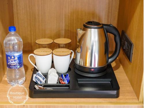 a tea kettle and cups on a tray on a counter at Saltstayz Select - Golf Course Road & Sector 57 in Gurgaon