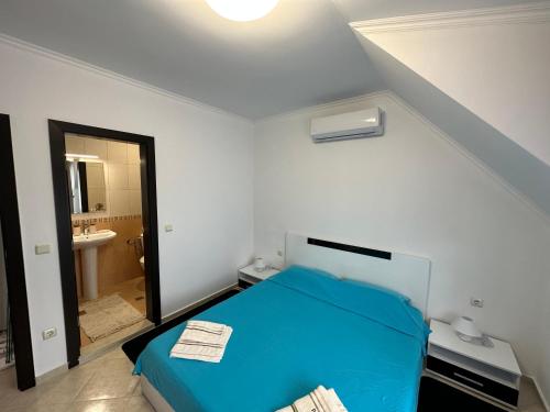 a bedroom with a blue bed and a bathroom at PANTELI APART HOUSE in Aheloy
