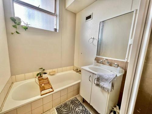 Baño blanco con bañera y lavamanos en Renovated Managers Apartment, en South Hedland
