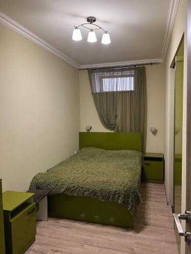 a bedroom with a green bed and a window at Appartment in the city center in Gyumri