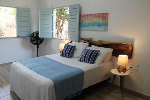 a bedroom with a bed with two pillows and two windows at Barra Beach House in Fortim