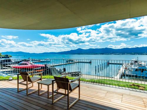 una terraza con sillas y vistas al agua en YANMAR SUNSET MARINA CLUBHOUSE&HOTEL en Moriyama