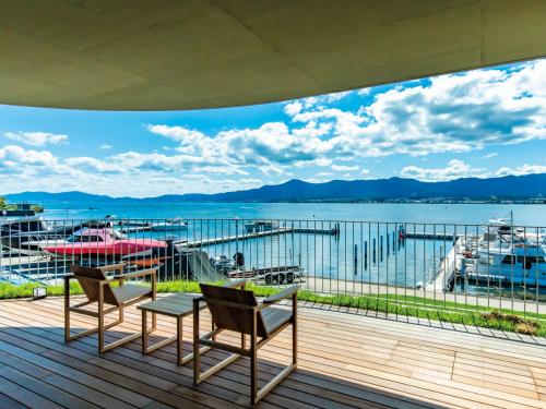 una terraza con sillas y vistas al agua en YANMAR SUNSET MARINA CLUBHOUSE&HOTEL, en Moriyama