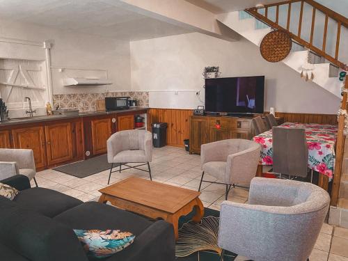 a living room with a couch and chairs and a tv at Gite les Bananiers in Saint-Joseph