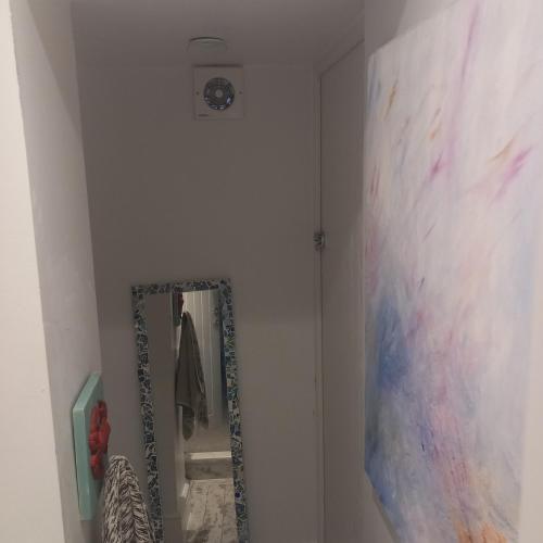 a bathroom with a mirror and a painting on the wall at Hideaway cottage - Studio ground floor with toilet and sink in Sandgate