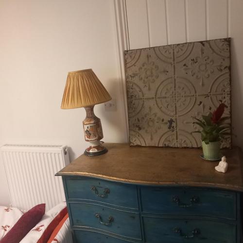 a lamp on top of a dresser in a bedroom at Hideaway cottage - Studio ground floor with toilet and sink in Sandgate