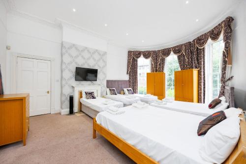 een grote witte slaapkamer met 2 bedden en een televisie bij Larger Groups Apartment close to Excel CanaryWharf 02 with Parking in Londen