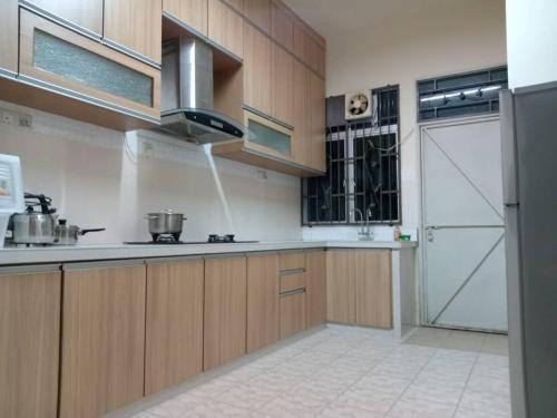 a kitchen with wooden cabinets and a refrigerator at BUTTERWORTH RAJA UDA RAYA HOMESTAY in Butterworth