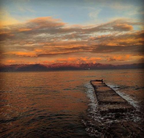 a pier in the water with a sunset at Kikkos Village House in Néa Koróni