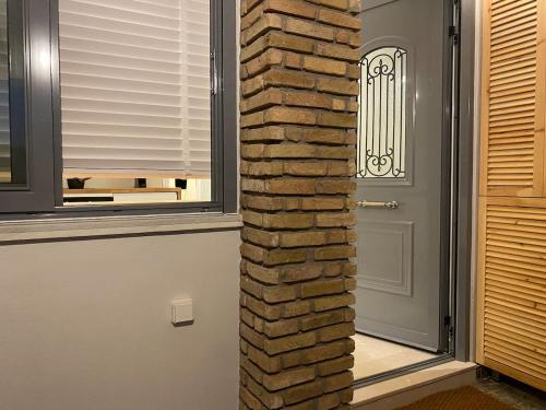 a brick wall next to a door with a window at Kikkos Village House in Néa Koróni
