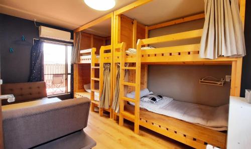 a room with two bunk beds and a couch at Guesthouse Yours in Osaka
