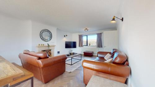 a living room with leather furniture and a tv at Low Greenlands Holiday Park - Luxury House & Luxury Glamping Pods in Lancaster