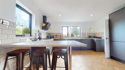 a kitchen with a large kitchen island with two stools at Low Greenlands Holiday Park - Luxury House & Luxury Glamping Pods in Lancaster