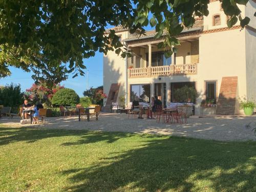 a large building with tables and chairs in a yard at Aux Coteaux d'Aussac in L Honor De Cos