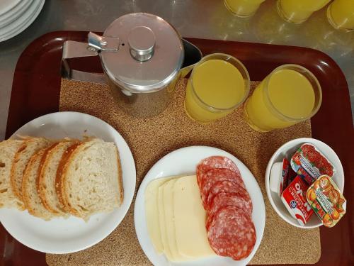 a tray of food with bread and sausage and glasses of orange juice at Ostria in Agia Galini