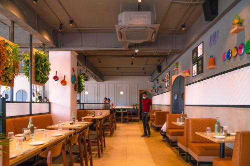 a restaurant with tables and chairs and a person standing in the middle at Aloka Stay Inn in Vellore