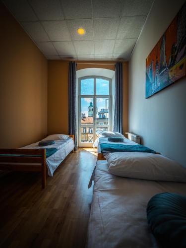 a room with three beds and a window at Hostel Pod Basztą in Lublin