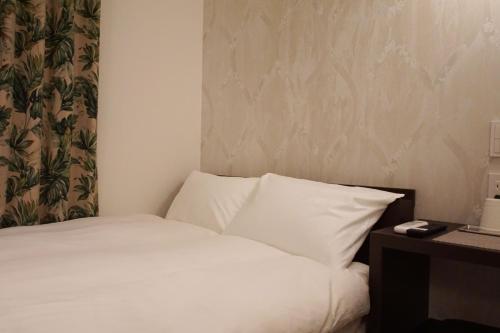 a bed in a hotel room with a pillow and a desk at MARUKOU HOTEL in Tokyo