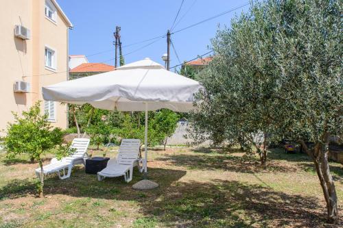 due sedie e un ombrellone in un cortile di Apartments Grgic a Trogir