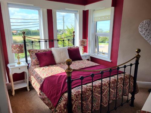 a bedroom with a bed and two windows at Ocean Retreat Norfolk in Trimingham